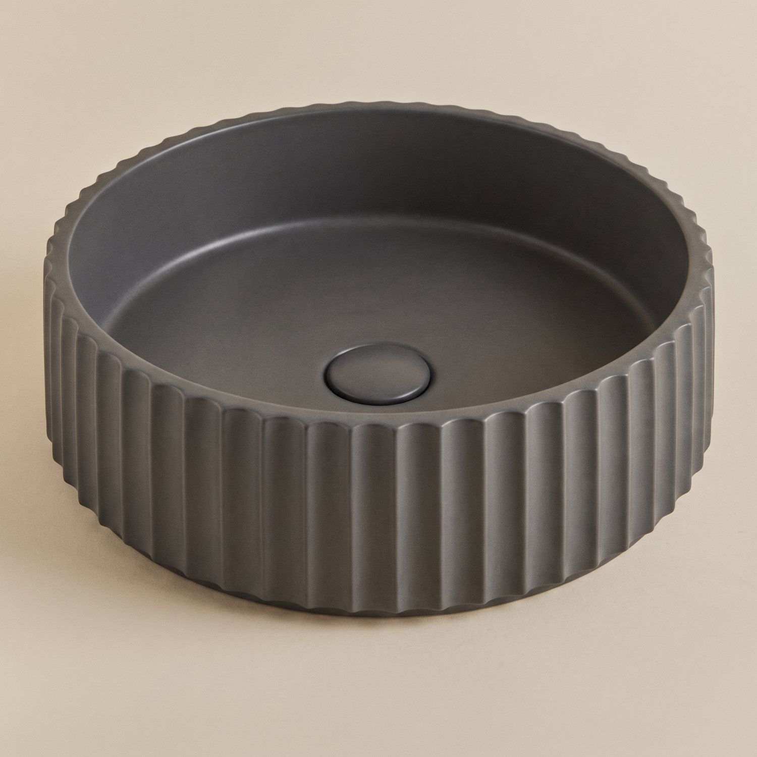 Lavabo de sobre encimera acanalado gris oscuro sobre fondo beige uniforme