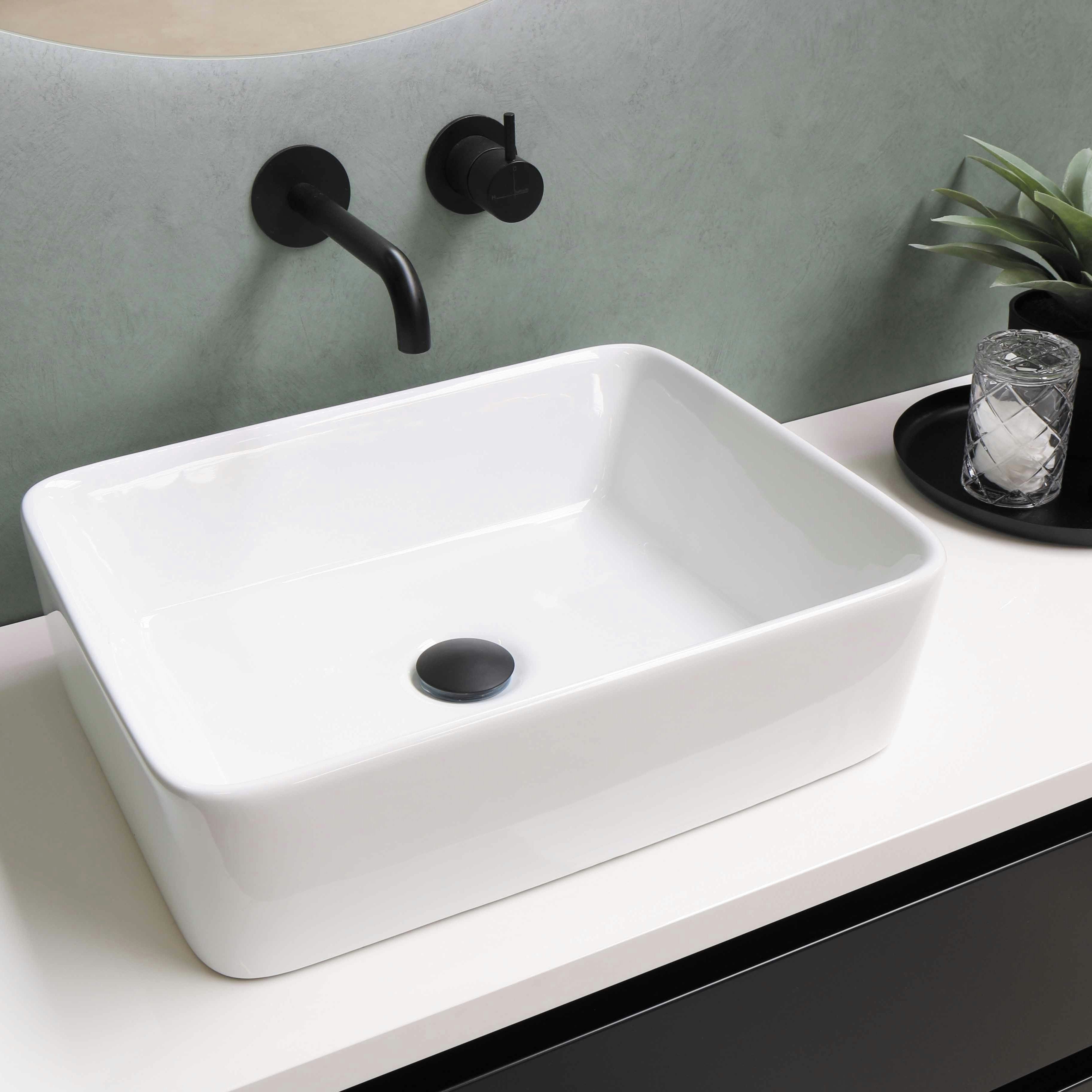 Lavabo blanco de sobre encimera en el baño junto con el grifo, la encimera y una planta